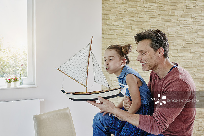 快乐的爸爸和女儿在家里玩模型船图片素材