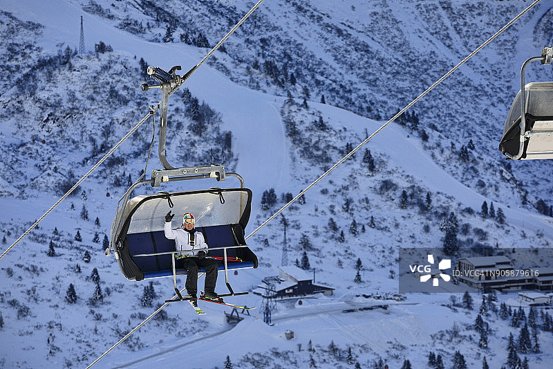 快乐的滑雪者在滑雪缆车上，向上。美丽的冬季景观，以山峰为背景。意大利阿尔卑斯山。白云石山脉。图片素材
