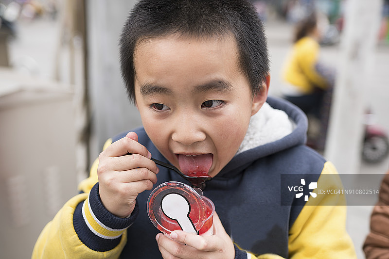 亚洲小学男孩吃果酱在街上高兴图片素材