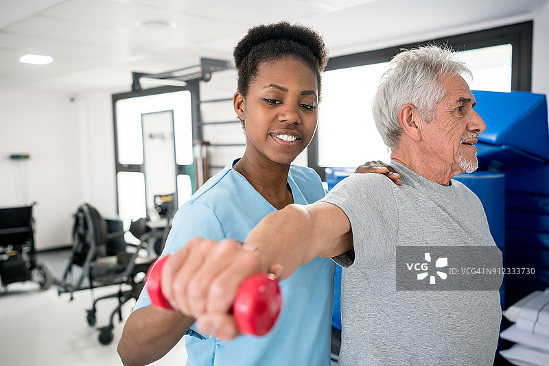 非裔美国职业治疗师帮助一位老年病人进行肩部锻炼图片素材