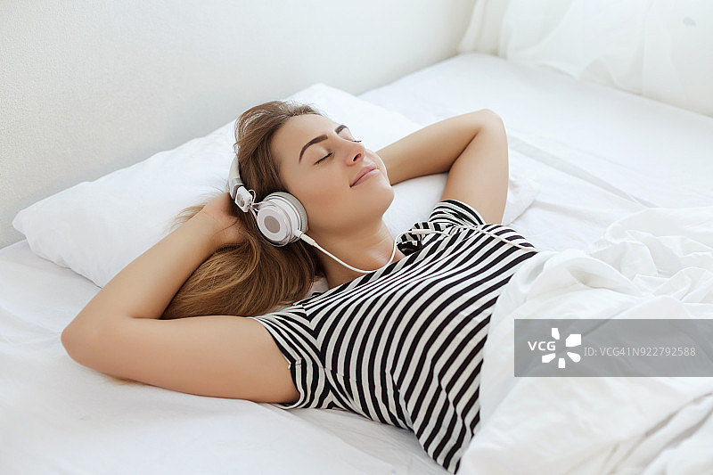年轻女子在床上听音乐图片素材