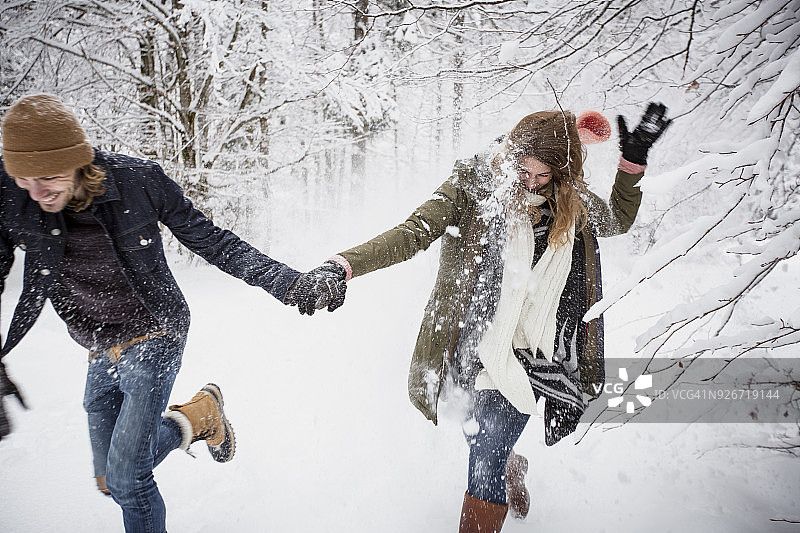 快乐的夫妇在冬天的森林里跑步图片素材