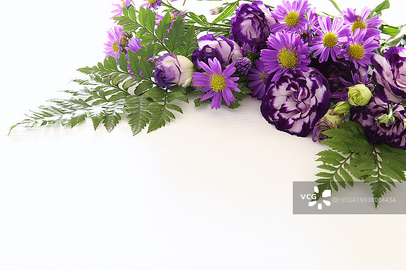 俯视图的紫色美丽的花安排在白色的木质背景。副本的空间。图片素材