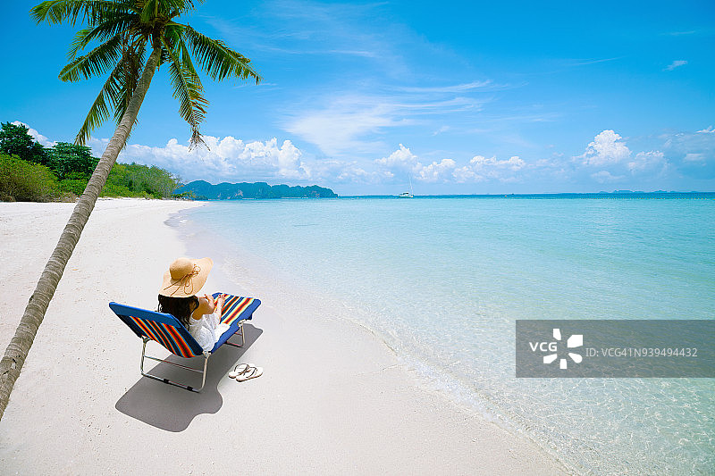 快乐的女人太阳帽上的沙滩躺椅，度假和旅行的概念图片素材