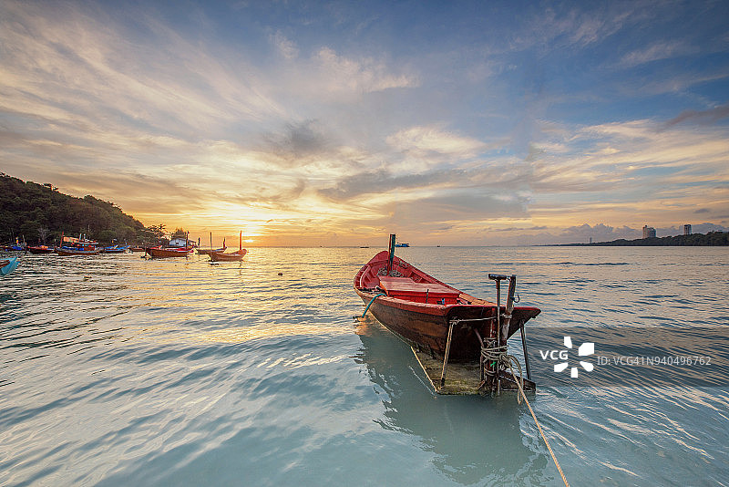 美丽的全景景观剪影渔舟漂浮在海上在黄昏的海滩和海面上的倒影。小船在海上黄昏时日落图片素材