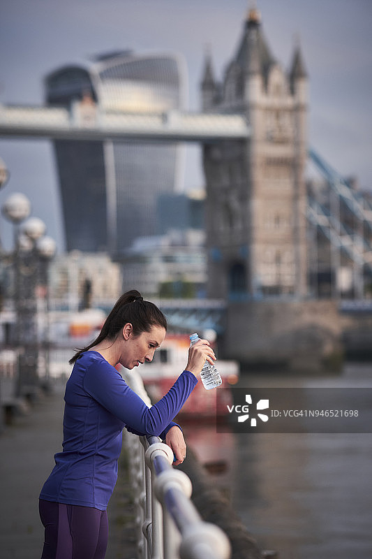 一名女子在伦敦泰晤士河边跑步后休息图片素材