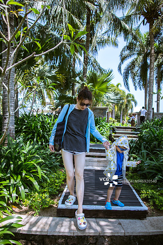一个年轻女子和她儿子牵着手走路的肖像图片素材