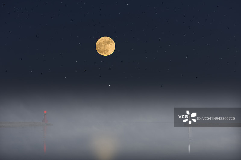 海面上升起的满月和浓雾中的灯塔图片素材