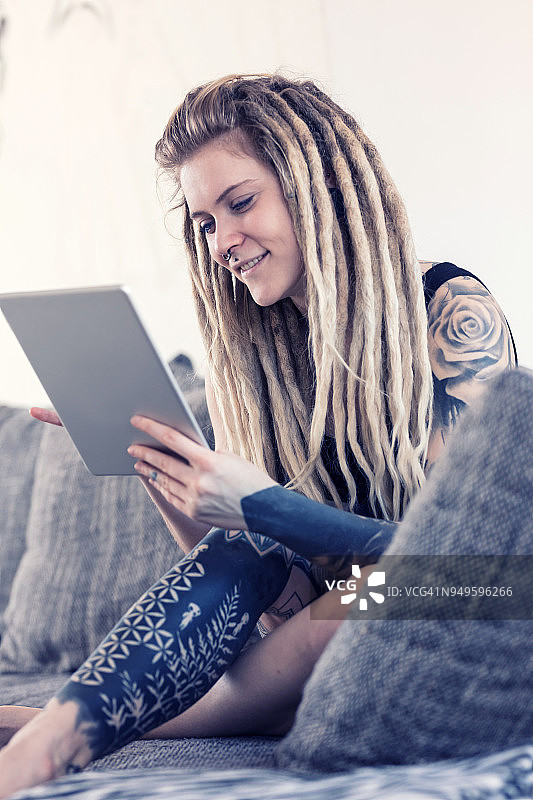 有纹身的年轻女子在家用平板电脑查看电子邮件图片素材
