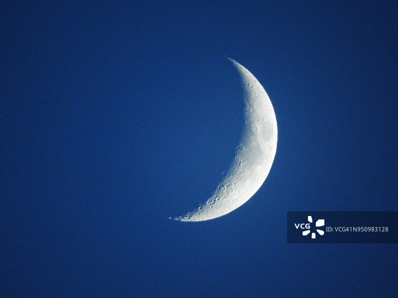 一弯新月对着蓝天的特写细节图片素材