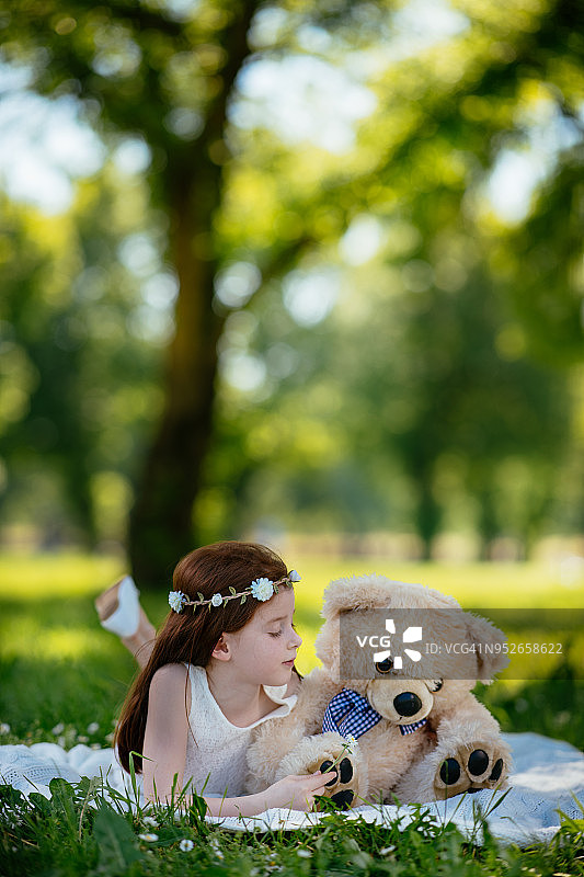 可爱的小女孩在公园里拥抱玩具熊图片素材