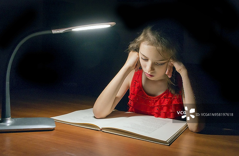 女孩在读一本有童话故事的书。图片素材