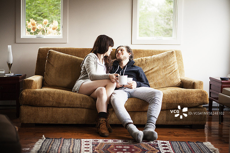 一对夫妇拿着咖啡杯坐在家里的沙发上图片素材
