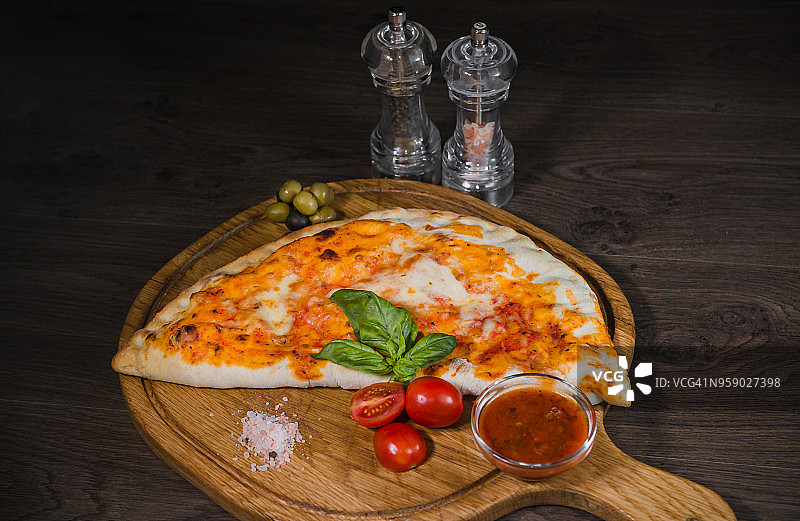 质朴的木桌上放着一块热披萨和融化的奶酪图片素材