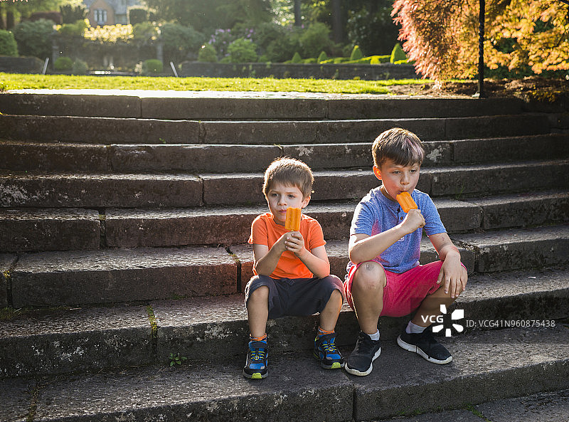 男孩们坐在台阶上吃冰棒图片素材