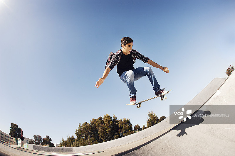 低角度的人表演特技在滑板公园对清澈的蓝色天空图片素材