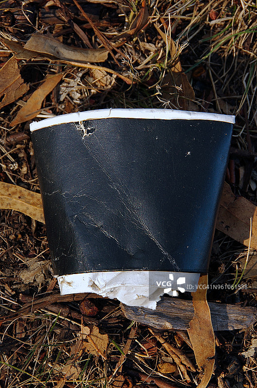被压碎的一次性硬纸板咖啡杯扔在公园的地上图片素材