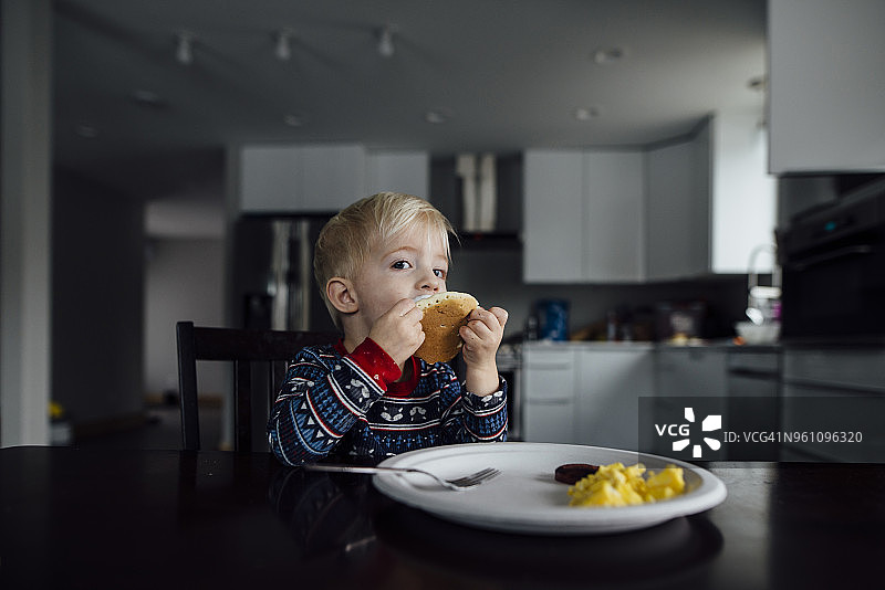 小男孩坐在家里餐桌边吃东西的照片图片素材