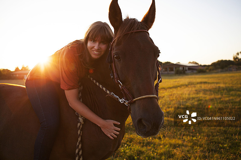 日落时骑马的微笑女人的肖像图片素材