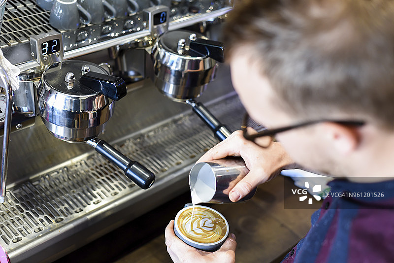 咖啡师将牛奶倒入咖啡中，同时制作起泡饮料图片素材