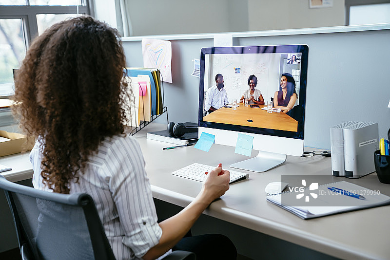女商人在办公室的桌上用电脑和同事进行视频会议图片素材