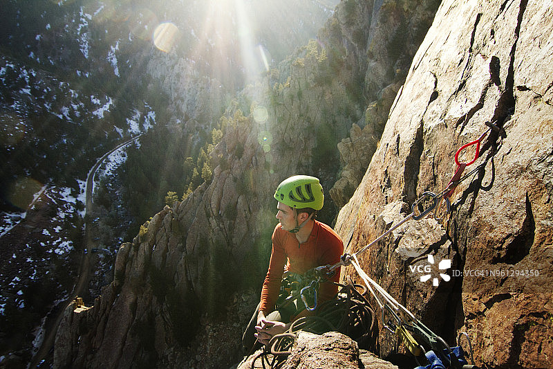 在一个阳光明媚的日子里，一个人在爬岩石山的时候看向别处图片素材