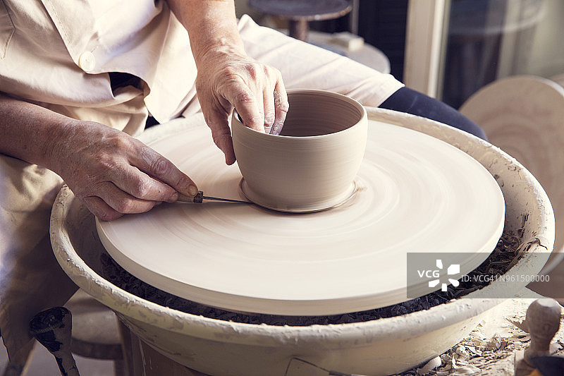 妇女在陶轮上用工作工具将陶土塑造形状图片素材