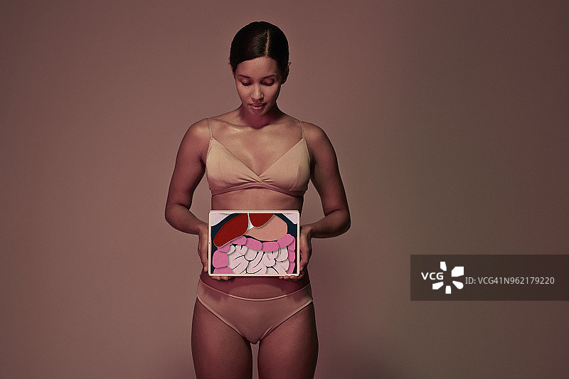 年轻女子拿着药片在胃前展示肠道图片素材