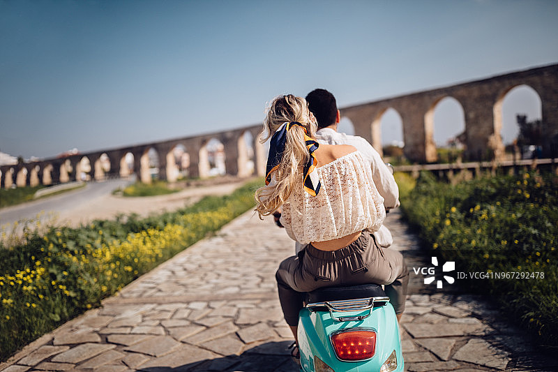 年轻的游客夫妇骑着复古摩托车经过古老的石碑图片素材