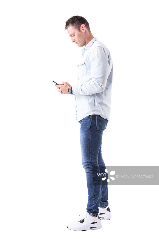 侧面的优雅的成年白人男子在手机上输入信息。图片素材