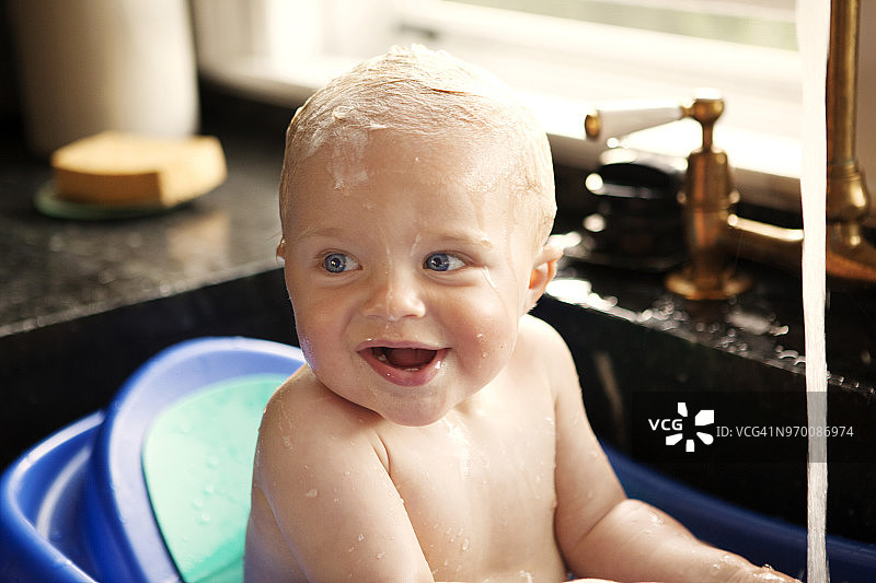 快乐的小男孩在厨房水槽洗澡的时候看向别处图片素材