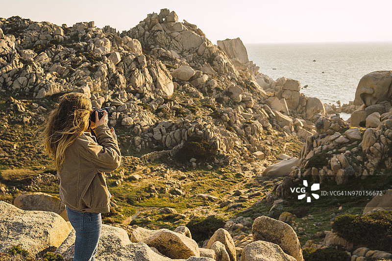 意大利，撒丁岛，妇女徒步旅行在海岸拍照图片素材