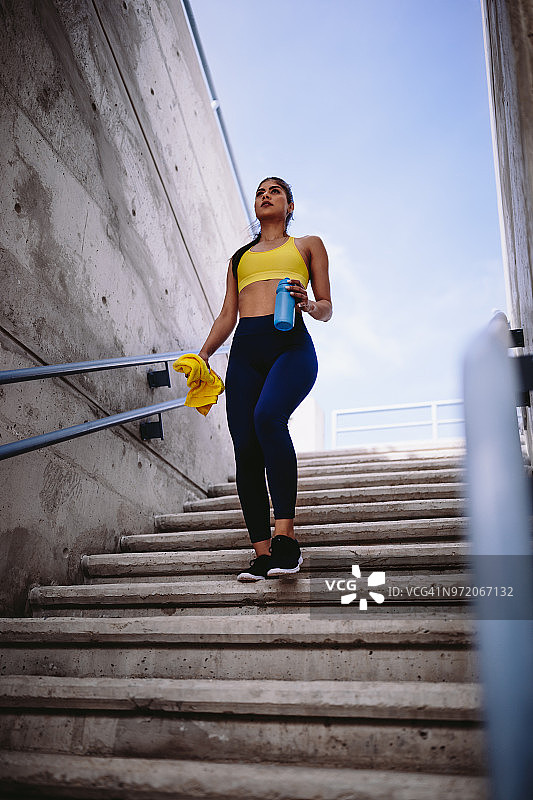 年轻的女运动员穿着运动服走下户外的楼梯图片素材