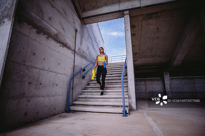 年轻女运动员准备训练走下城市的楼梯图片素材