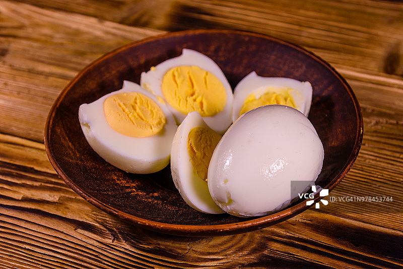 陶瓷盘子和去皮煮鸡蛋放在木桌上图片素材