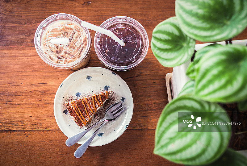 咖啡馆的木桌上放着冰咖啡蛋糕和植物自然叶。图片素材