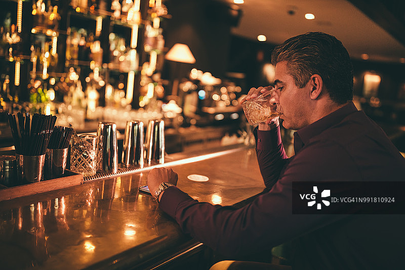 优雅成熟的男人在酒吧喝酒，看时间图片素材