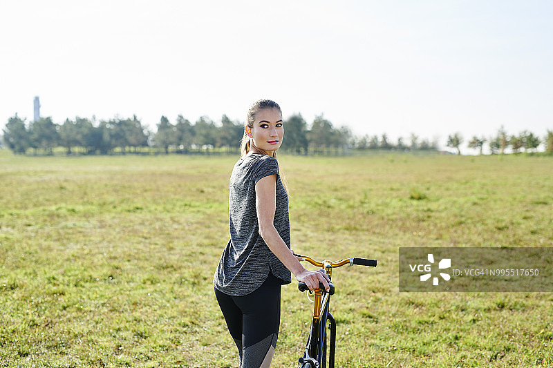 在草地上骑自行车的年轻女子图片素材