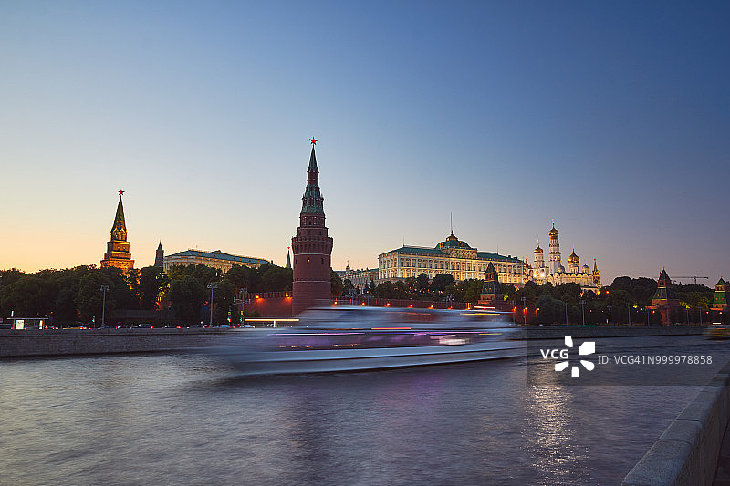 日落时分的莫斯科克里姆林宫全景。莫斯科河的前景是一艘游船。图片素材