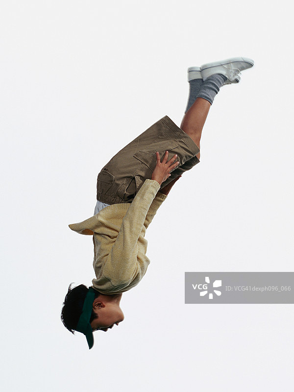 年轻的亚洲男孩在短裤和运动衫，跳在半空中图片素材