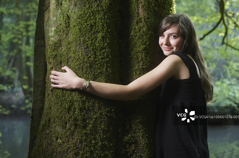英国，梅尔斯，萨默塞特，年轻女子拥抱树在森林，肖像图片素材