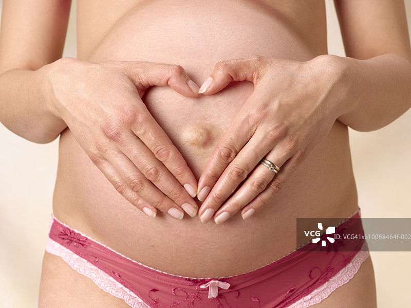 孕妇双手放在腹部呈心形，特写，腹部图片素材