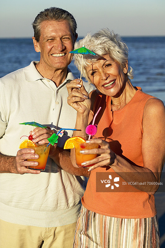 丈夫和妻子在海滩上拿着鸡尾酒的肖像图片素材