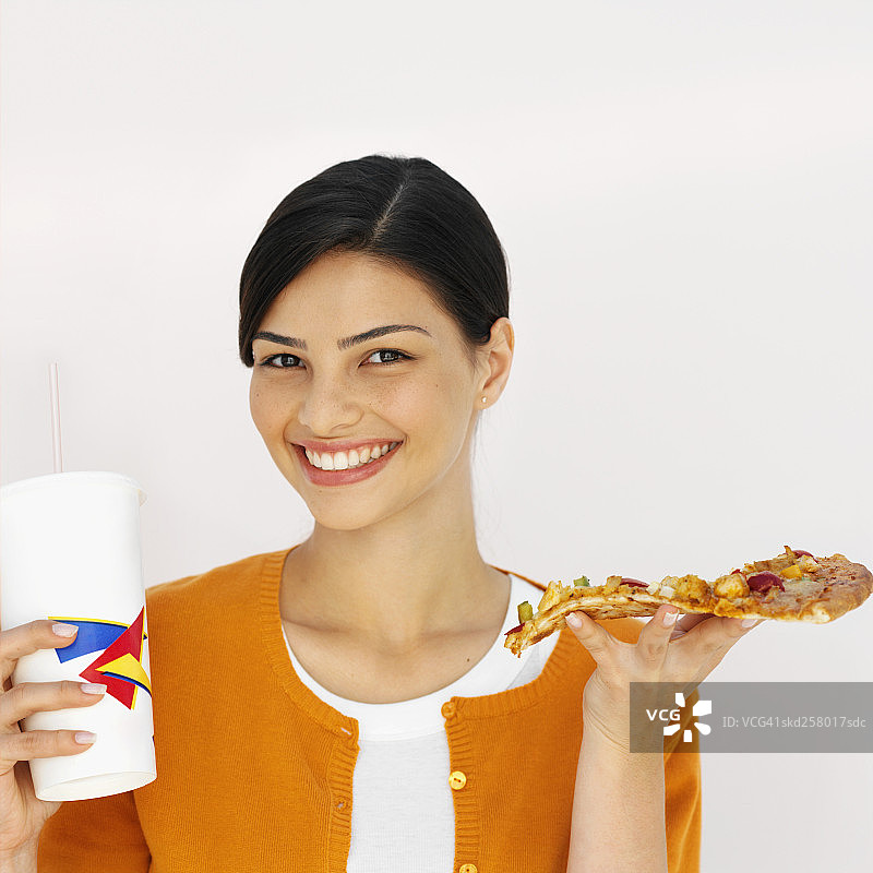 特写的年轻女子持有一片披萨和饮料图片素材