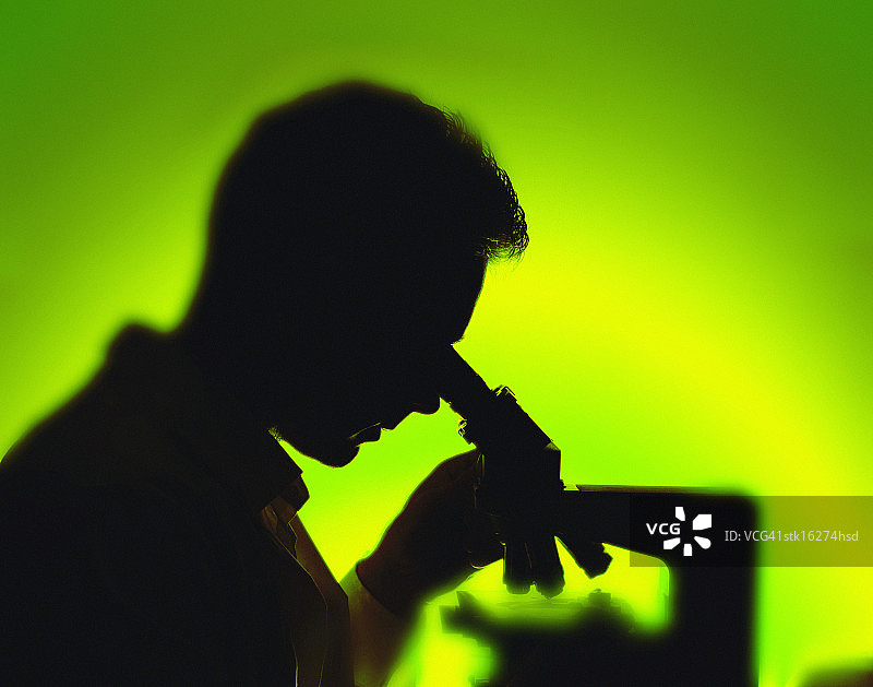 一个看着显微镜镜头的男人的剪影图片素材