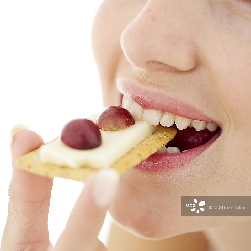 一个女人把一个饼干和奶酪在她的嘴的特写图片素材
