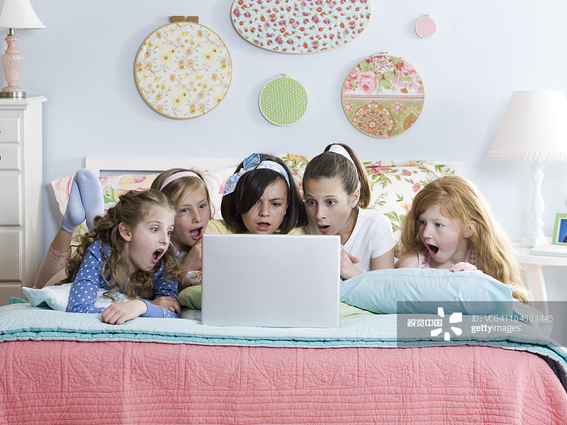 五个女孩在床上用笔记本电脑图片素材