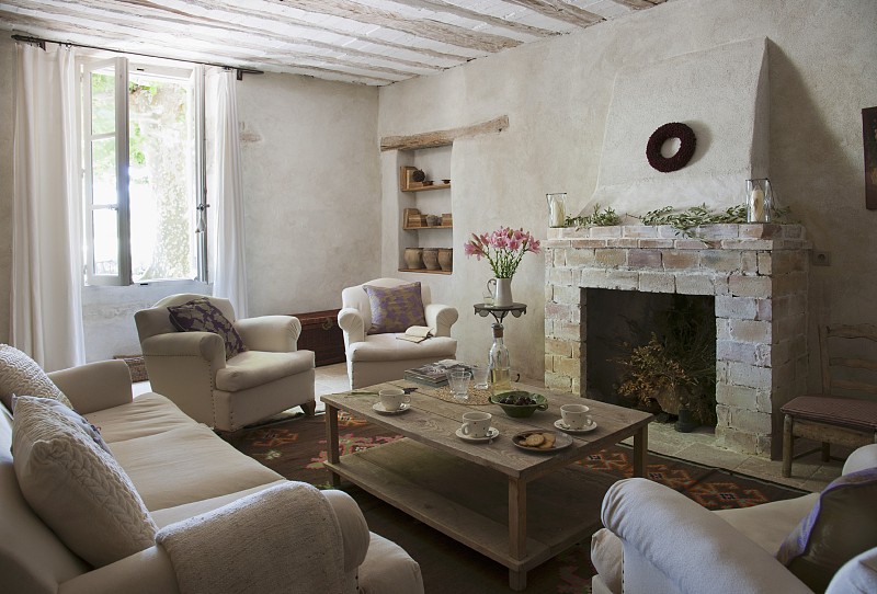 在质朴的壁炉前，有软垫家具和简单的咖啡桌的座位区;架子在砖石壁龛的背景图片下载