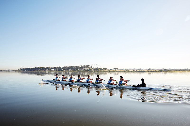 女子赛艇队在宁静的湖面上划桨图片下载