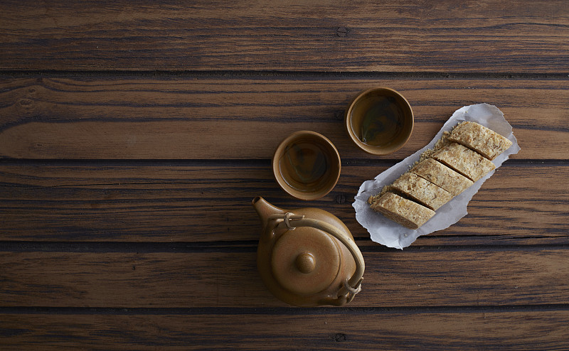 木桌上的糖棒、花生、中国甜点和热茶图片下载
